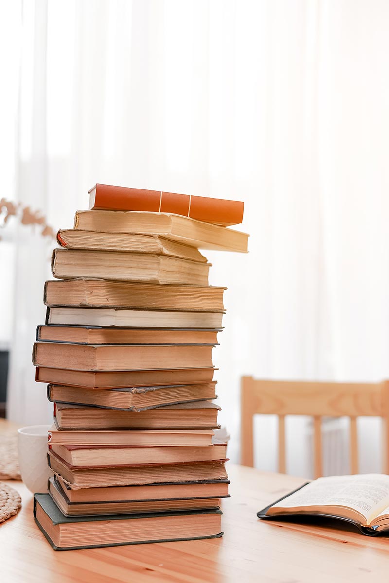 vecteezy_stack-books-or-textbooks-and-one-opened-book-on-wooden-desk_16693960